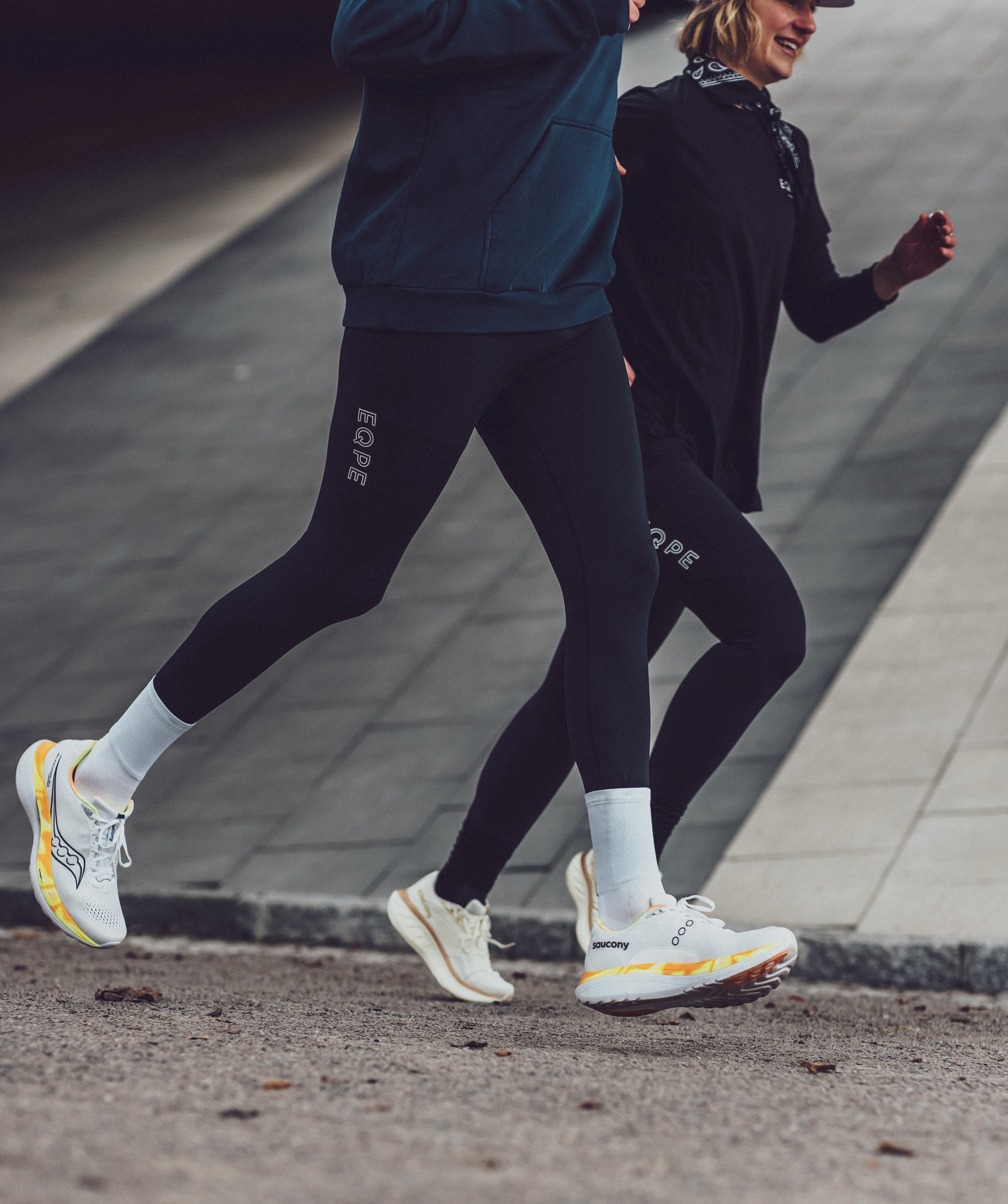 Two people jogging outdoors, wearing athletic gear.